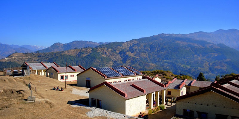 nepalese school with solar system installed and mountains and blue sky in background