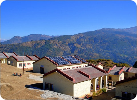 nepalese school with solar system installed and mountains and blue sky in background