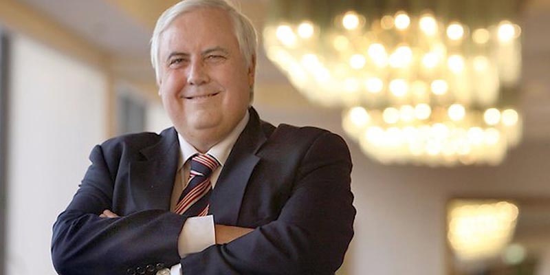 clive palmer in a suit with arms crossed looking happy