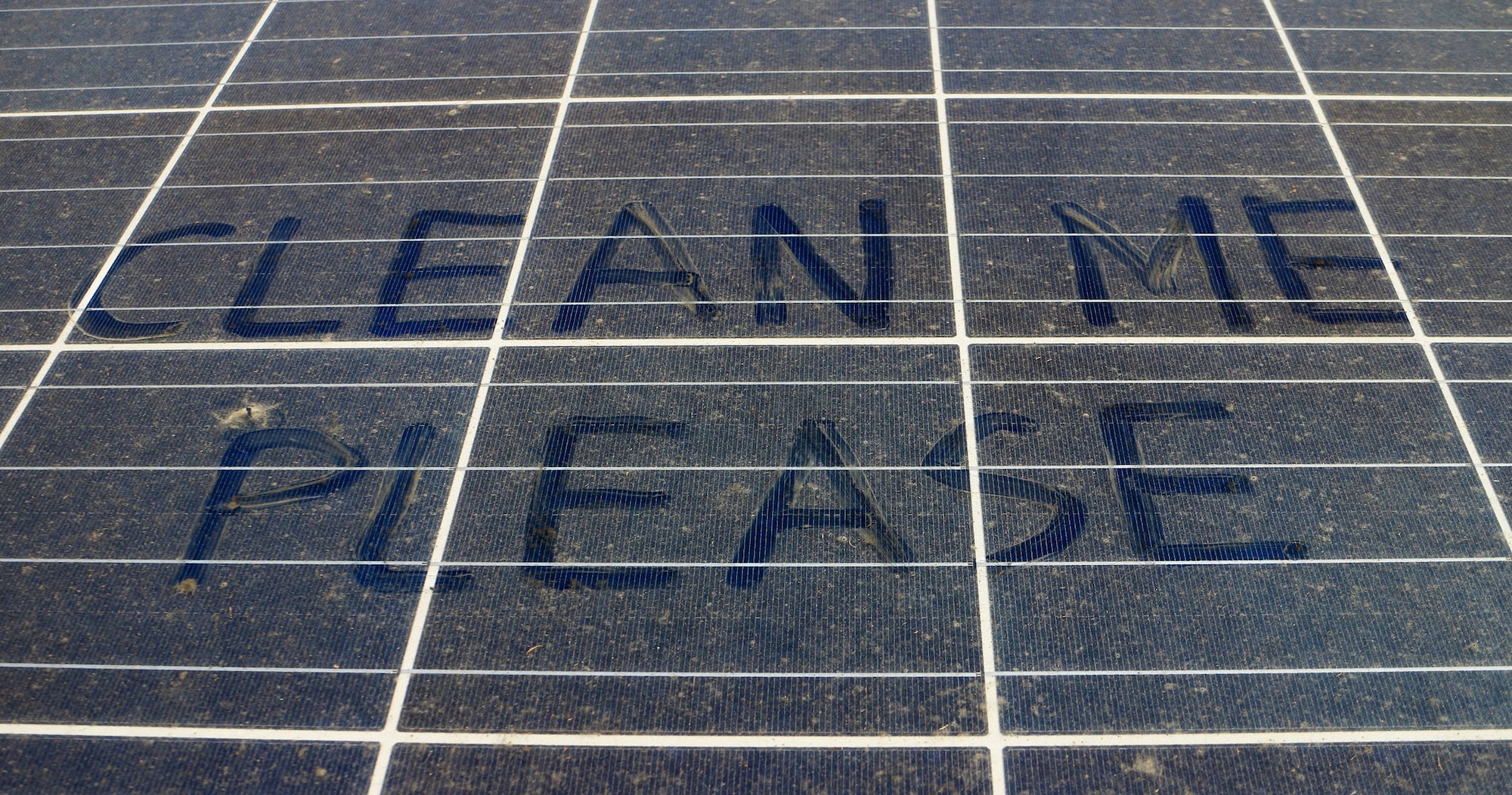 clean me please written on dirty solar panels