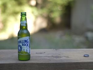 A bottle of Rolling Rock and its bottle cap
