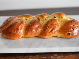 Baked braided egg bread (challah) on a marble slab ready to be cut