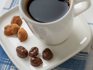chocolate-covered coffee beans with cup of brewed coffee