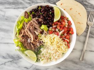 bowl of copycat carnitas with lime wedges