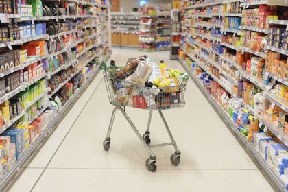 A packed grocery cart in an empty grocery aisle 