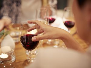 Close up of woman holding red wine at a group dinner