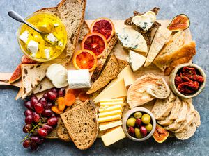 a wooden board with various breads and cheeses