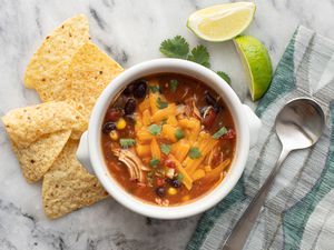 bowl of tortilla soup with cheese, cilantro, and tortilla chips