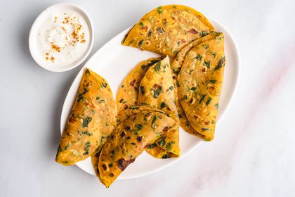 Methi Paratha (Fenugreek Paratha) on a plate, served with a side of sauce 