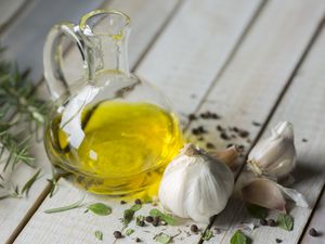 Olive oil in a cruet, garlic, and herbs