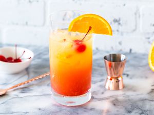 Tequila sunrise with a maraschino cherry and orange slice