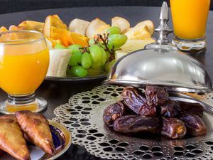 Regional Food Backgrounds. Dried date palm fruits, fresh orange juice, samosa snack and blurred fruit background concept iftar in the holy month Ramadan.
