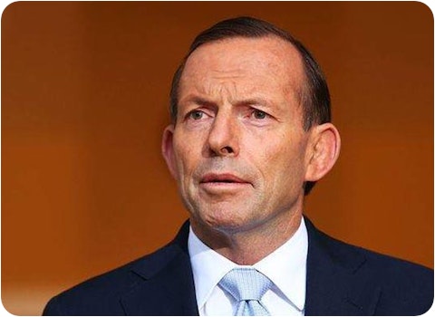 tony abbott in suit standing next to australian flag 