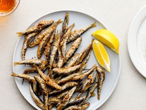 Classic Fried Whitebait (Fried Tiny Fish), fried fish and lemon wedges on a plate 