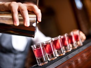 Bartender pouring pink shots into shot glass