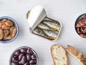 variety of canned seafood products and bread on light wooden surface