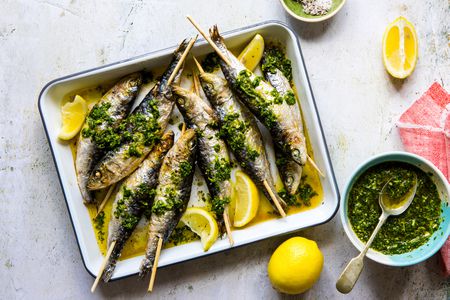 A dish of skewered sardines with lemons