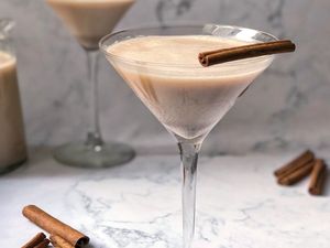 spiked horchata in a martini glass with stick of cinnamon as garnish