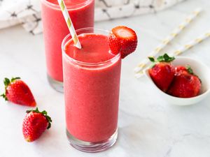 Two glasses of strawberry smoothies with strawberry garnish