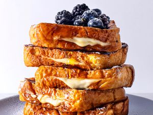 Stack of stuffed french toast with blueberries and blackberries on a plate.